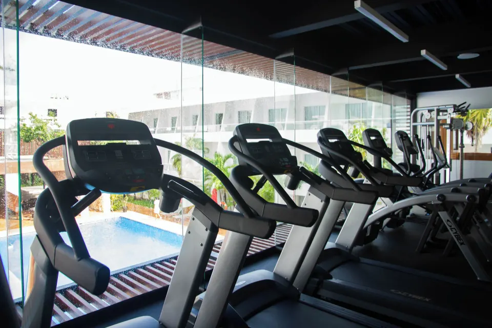 Cardio machines overlook the pool through glass at Cancun Bay Hotel.