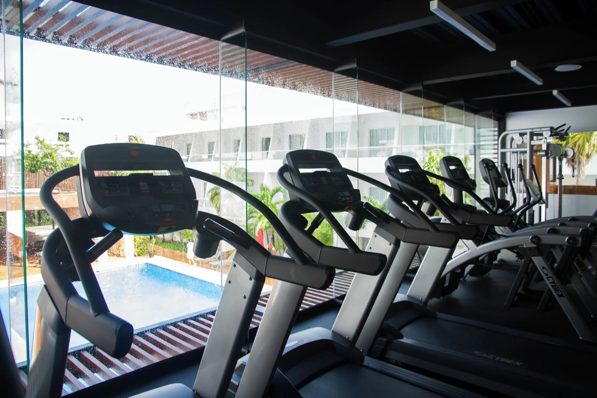 Cardio machines overlook the pool through glass at Cancun Bay Hotel.