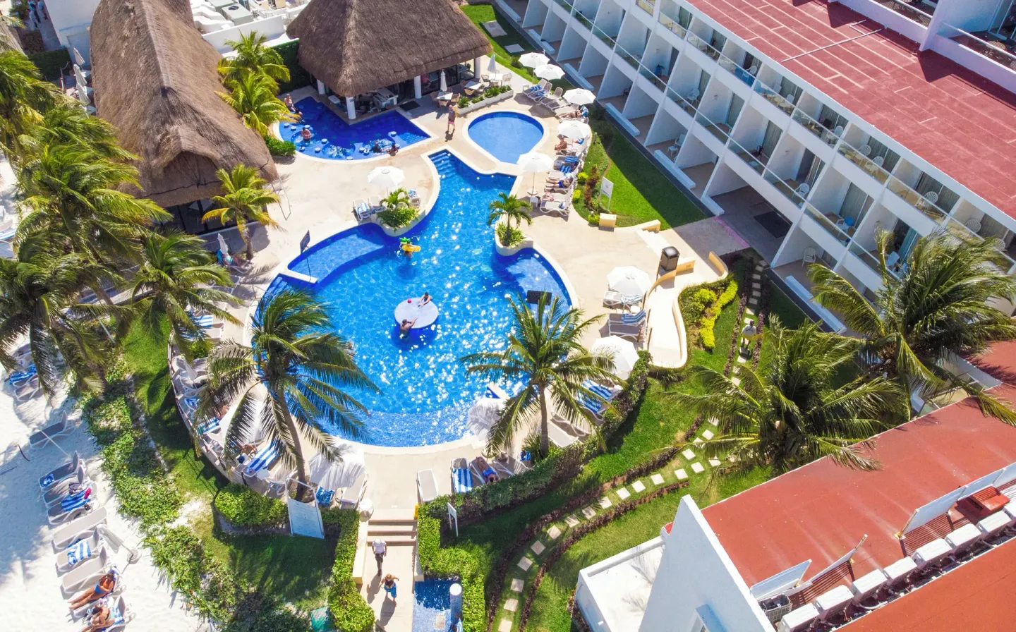 Aerial view of the main pool, palms, loungers, and guest room wing at Cancun Bay Hotel.