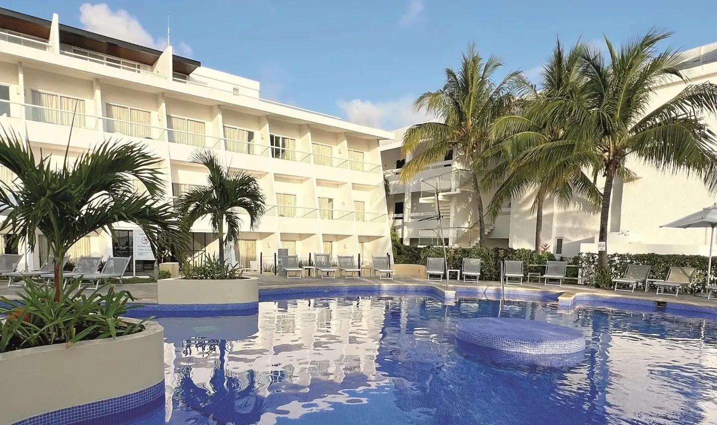 Pool courtyard with palm trees and guest room balconies at Cancun Bay Hotel.