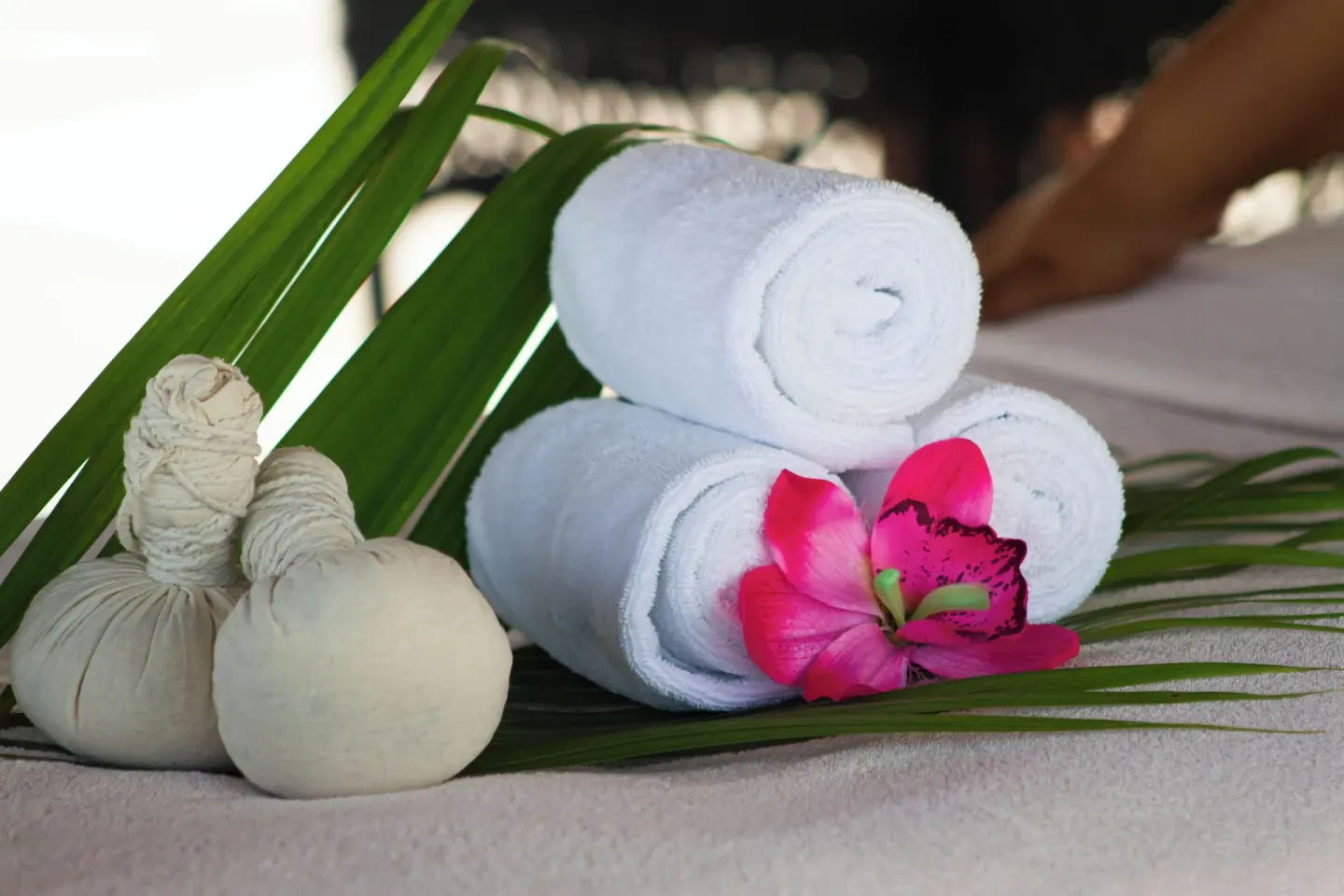 Rolled towels, herbal compresses, palm leaves, and a flower at Cancun Bay Hotel.