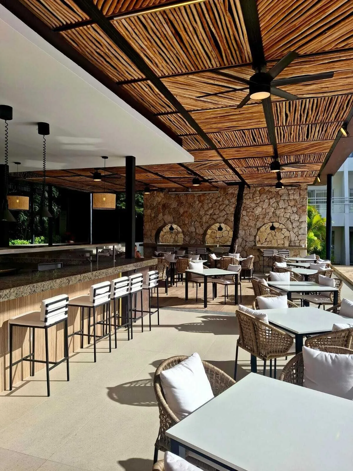 Covered terrace bar seating with wicker chairs and stone accents at Cancun Bay Hotel.