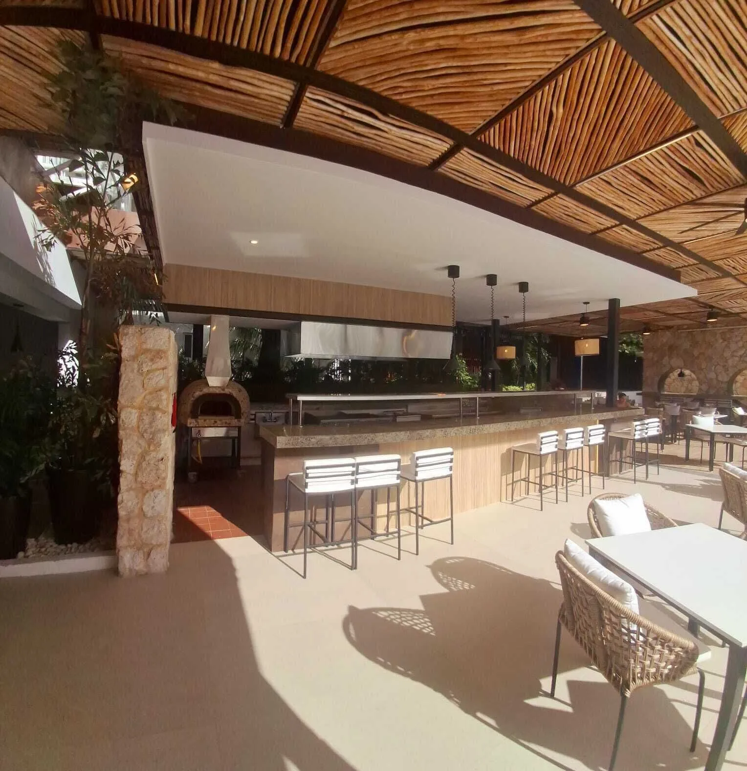 Open-air restaurant counter with bar stools and a pizza oven at Cancun Bay Hotel.