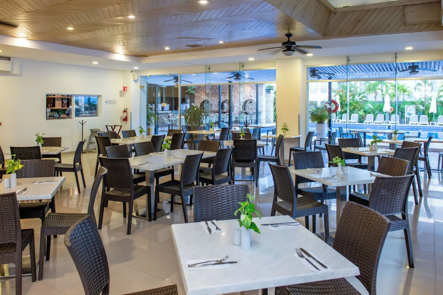 Casual dining room with marble-look tables and pool views at Cancun Bay Hotel.