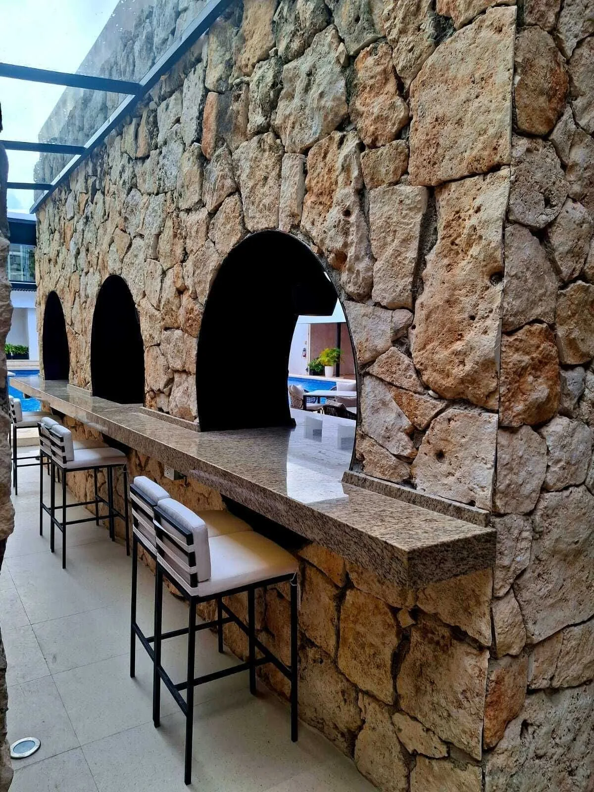 Stone bar counter with arched openings and stools at Cancun Bay Hotel.