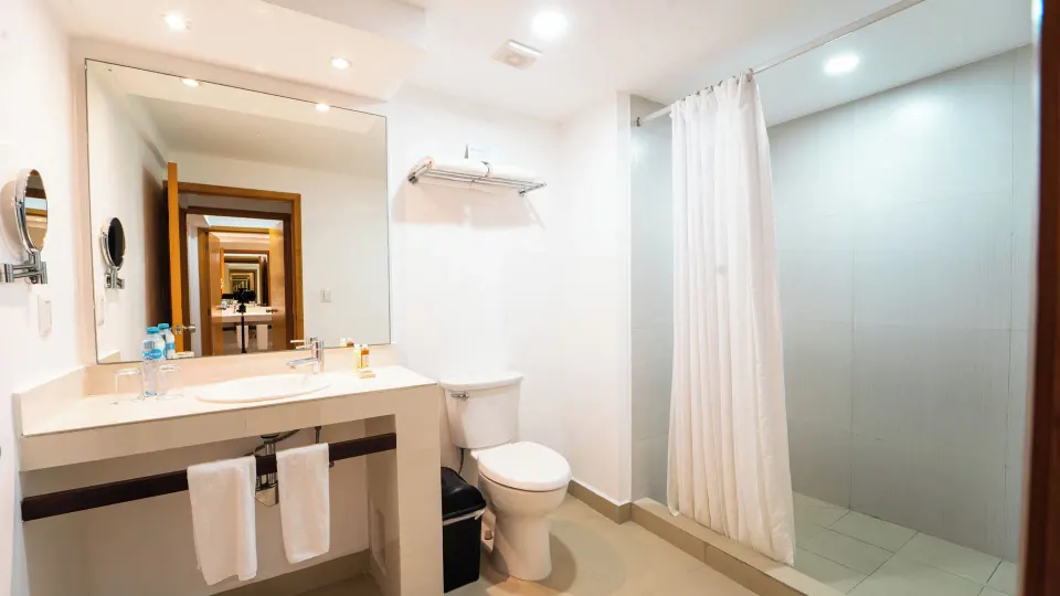 Junior Suite bathroom with vanity and curtained shower at Cancun Bay Hotel.