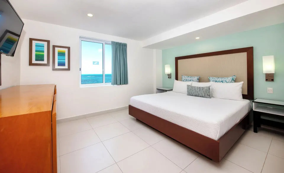 Junior Suite bedroom with king bed and sea-view window at Cancun Bay Hotel.