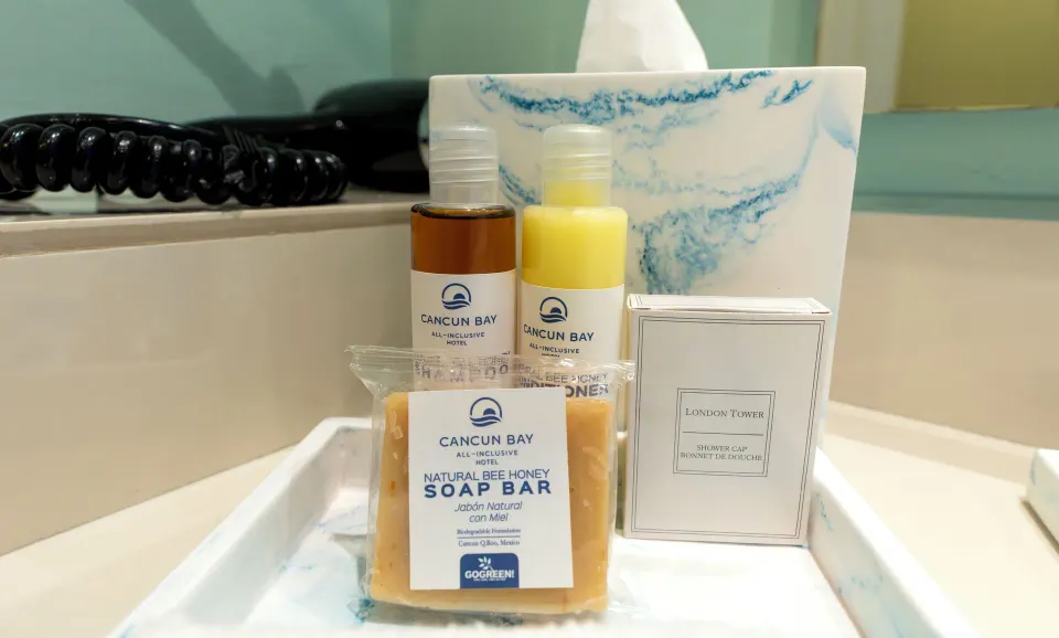 Standard Room toiletries at Cancun Bay Hotel with soap, bottles, shower cap and tissue box on a tray.