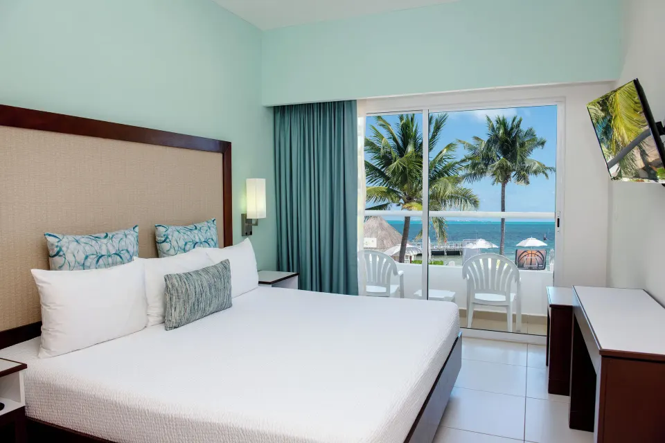 Superior Ocean View room with one bed, balcony chairs, palms, and sea at Cancun Bay Hotel.
