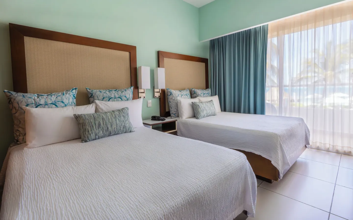 Superior Ocean View room with two beds and sheer balcony curtains at Cancun Bay Hotel.