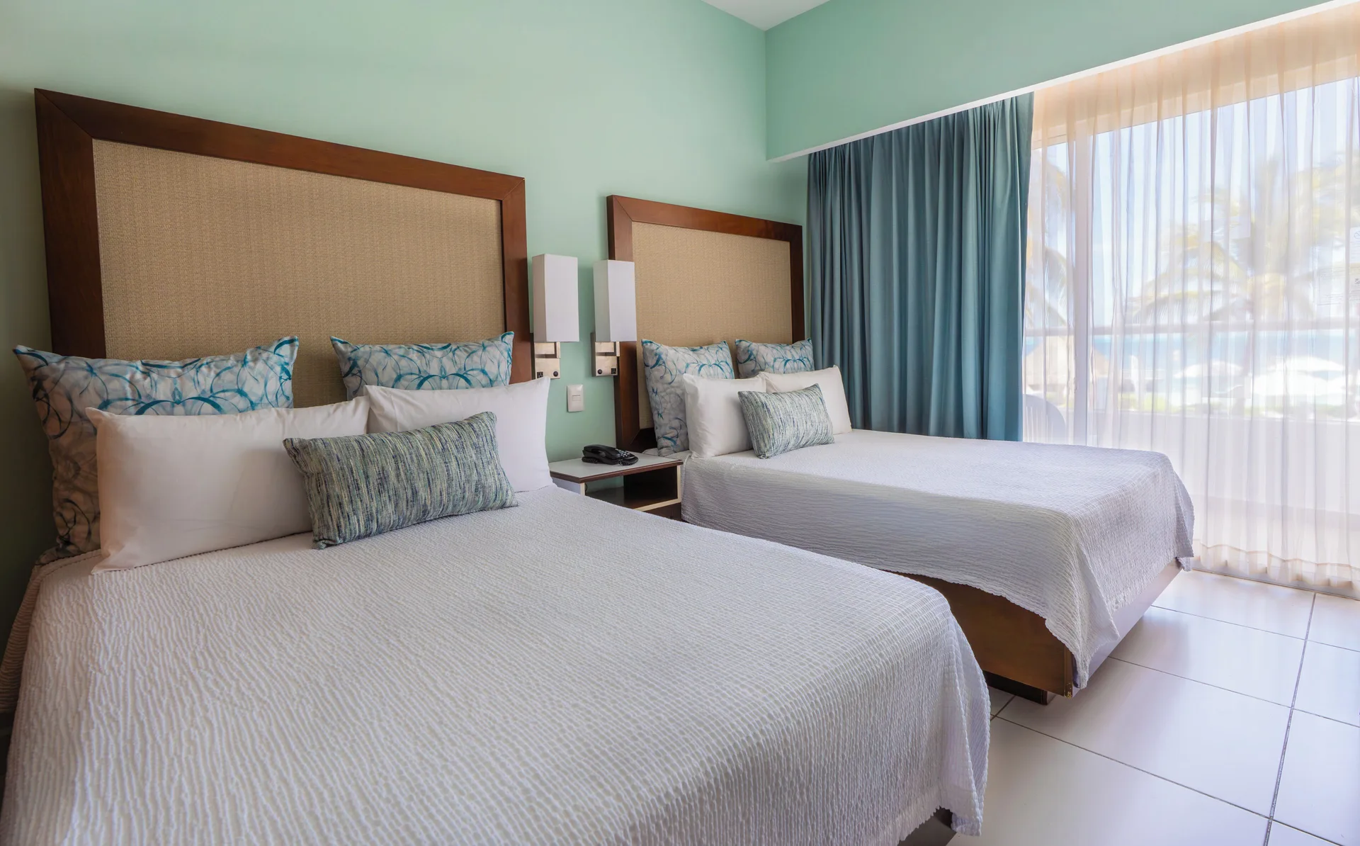 Superior Ocean View room with two beds and sheer balcony curtains at Cancun Bay Hotel.
