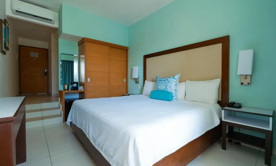 Standard Room with a king bed, wardrobe, and nightstands at Cancun Bay.