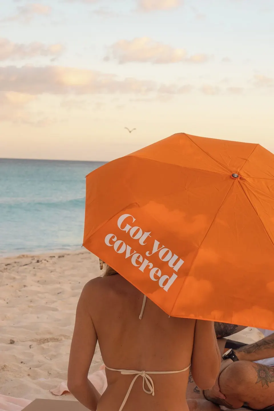 Orange beach umbrella shading guests at sunset on a Cancun beach near Canopy by Hilton Cancun La Isla.