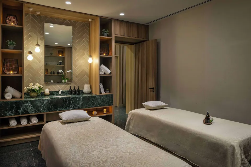 Spa room with two massage tables and green stone vanity at Canopy by Hilton Cancun La Isla.
