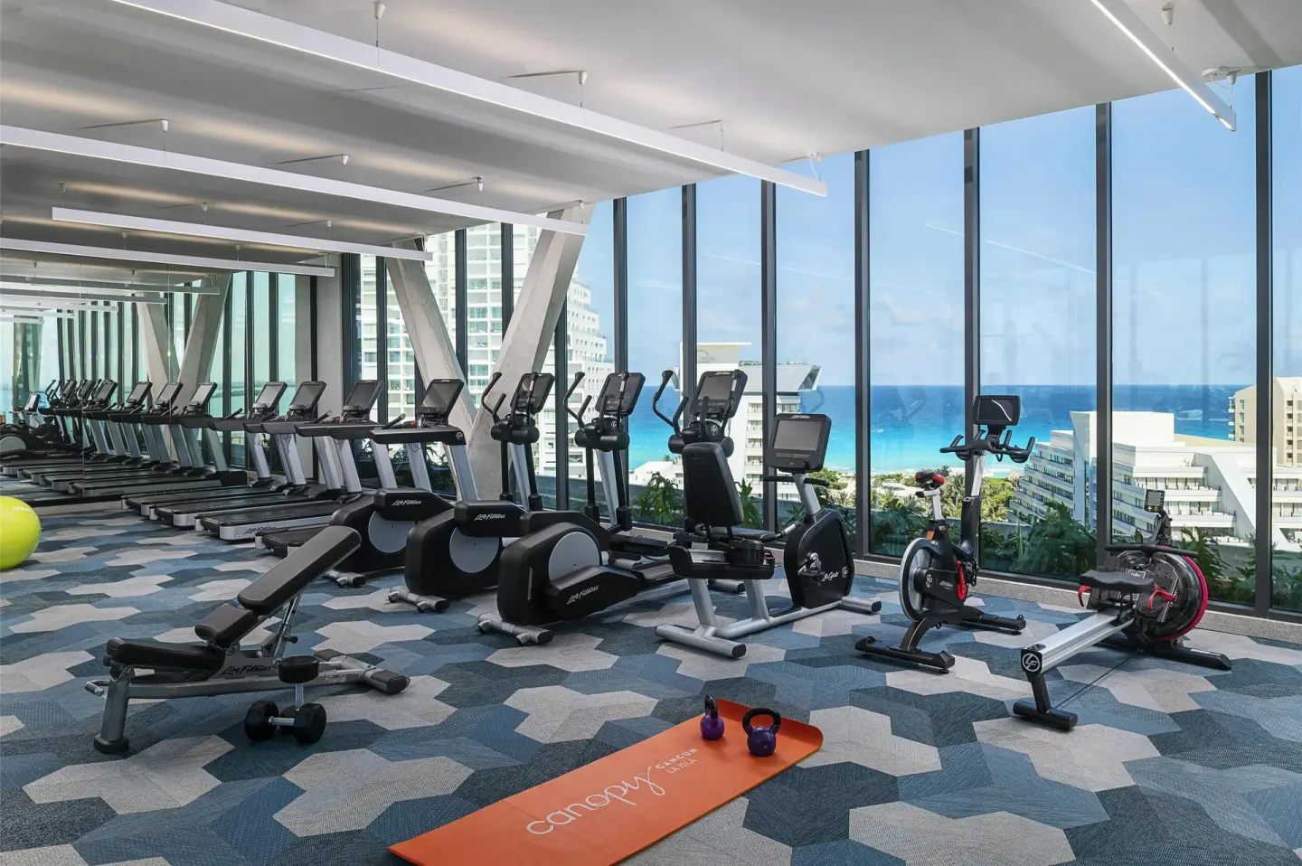 Cardio machines and yoga mat in the fitness center at Canopy by Hilton Cancun La Isla.