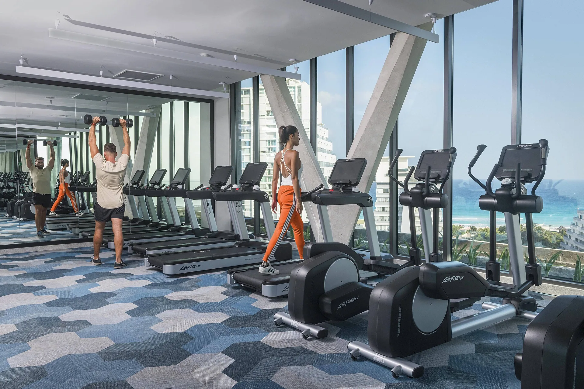Fitness center with treadmills and ocean-facing windows at Canopy by Hilton Cancun La Isla.