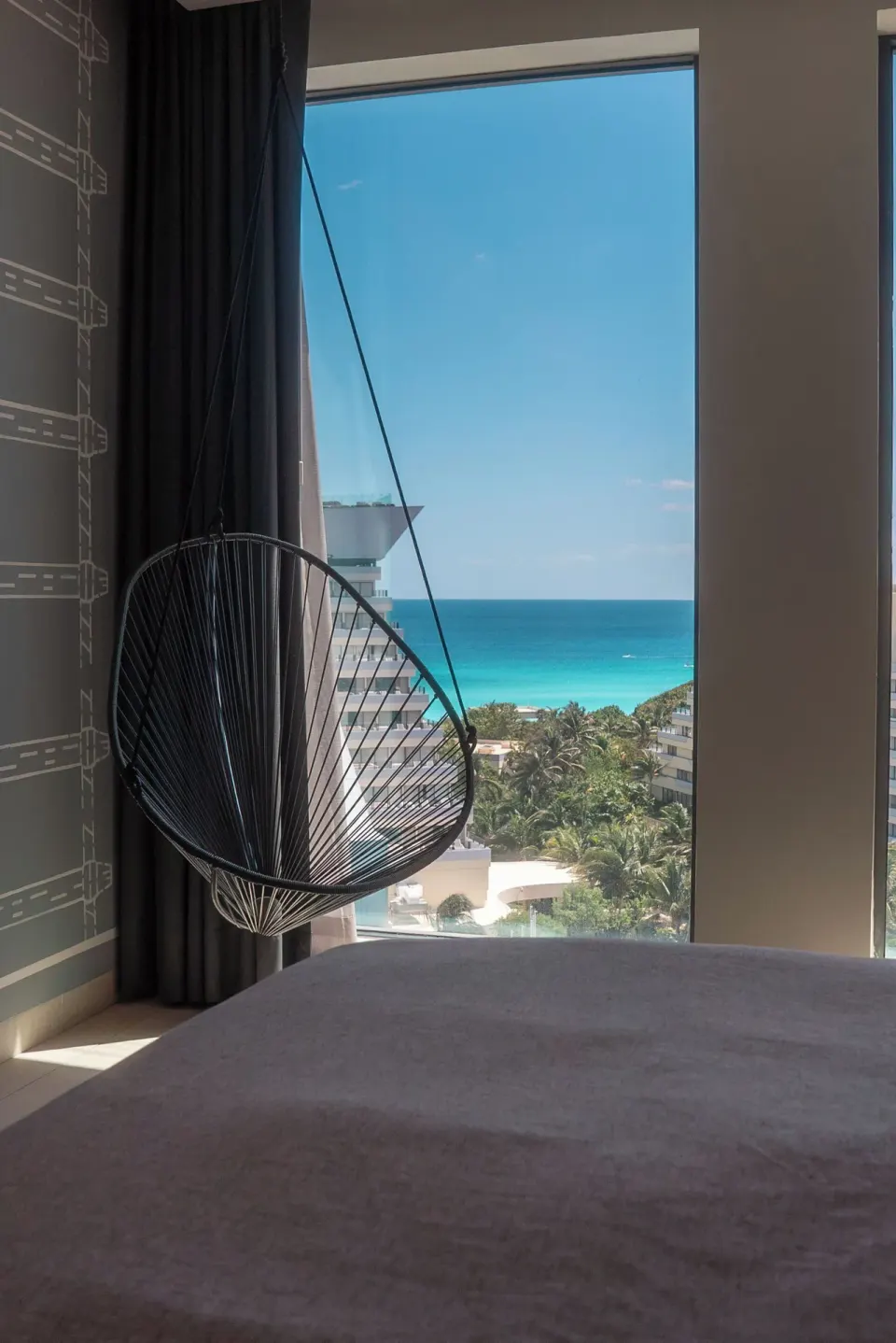Hanging chair by a guest room window with ocean view at Canopy by Hilton Cancun La Isla.
