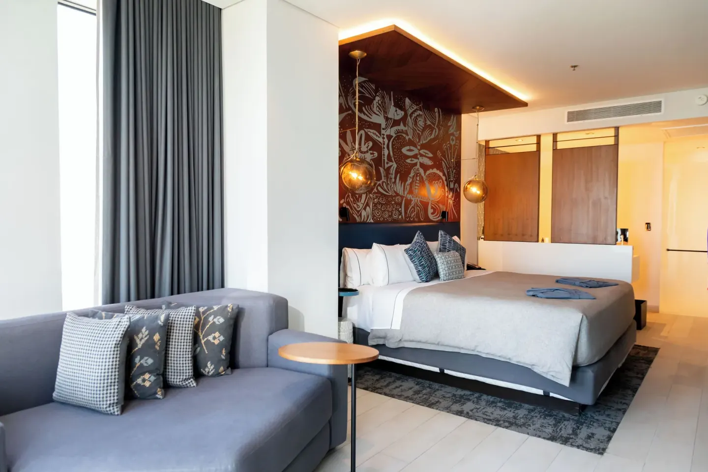 King guest room with sofa seating and patterned headboard wall at Canopy by Hilton Cancun La Isla.