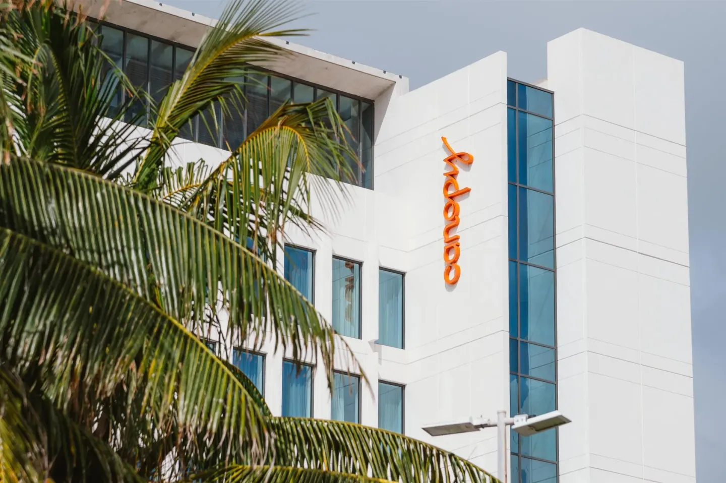 Palm fronds frame the white exterior of Canopy by Hilton Cancun La Isla.