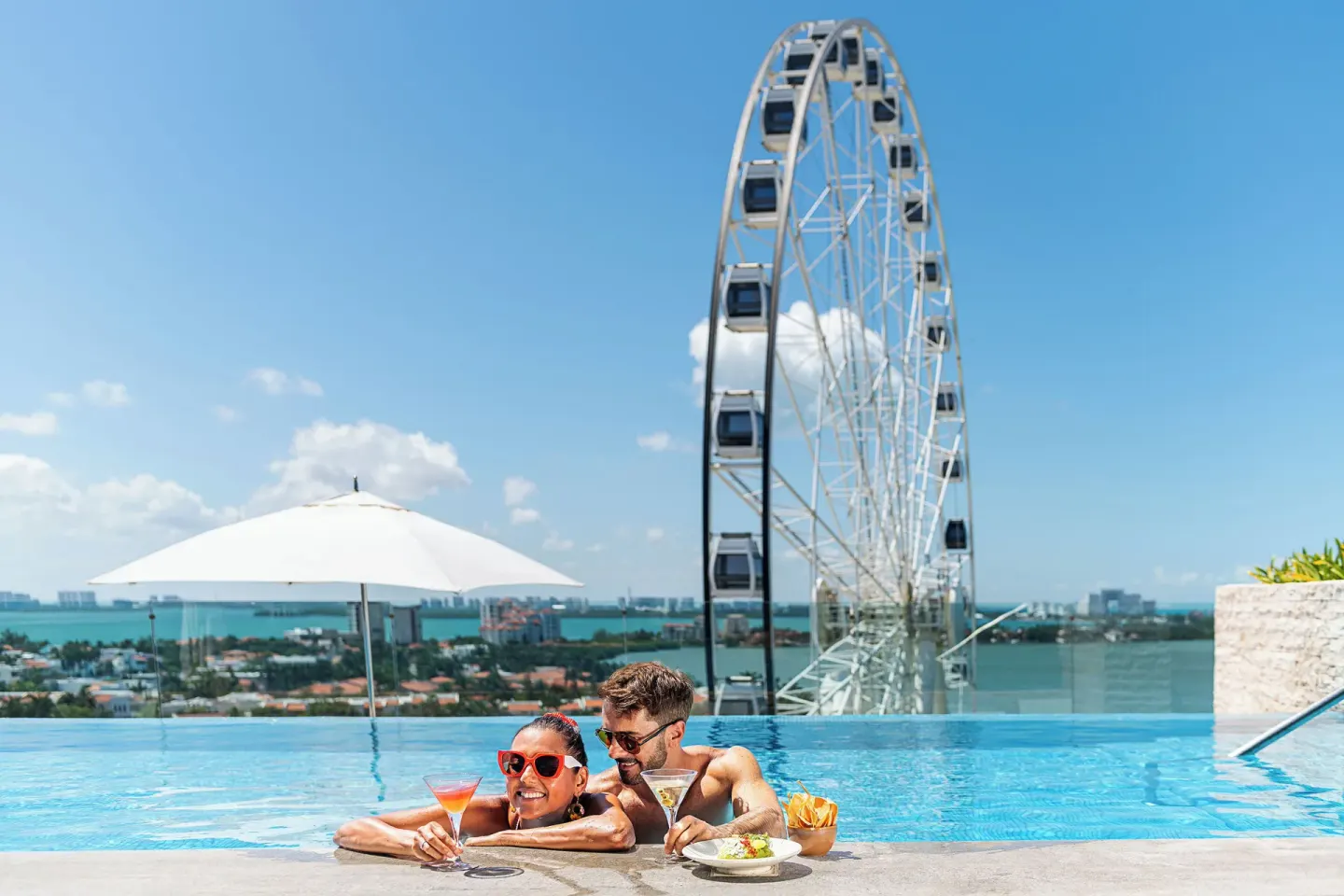 Couple in the rooftop pool with drinks at Canopy by Hilton Cancun La Isla.
