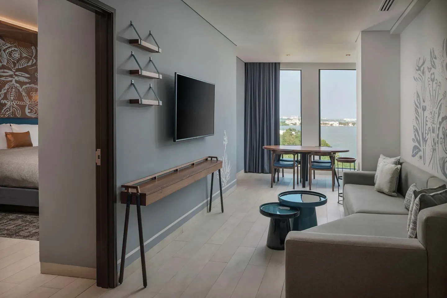 Junior Suite living room with sofa, TV, dining table, and lagoon view at Canopy by Hilton Cancun La Isla.