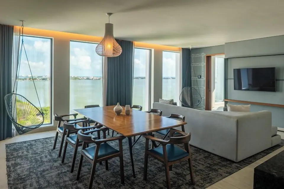 Presidential Suite living and dining area with bay windows at Canopy by Hilton Cancun La Isla.