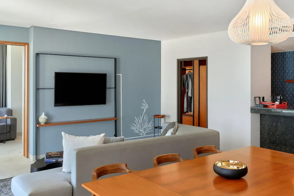 Presidential Suite living room with TV, dining table and closet at Canopy by Hilton Cancun La Isla.