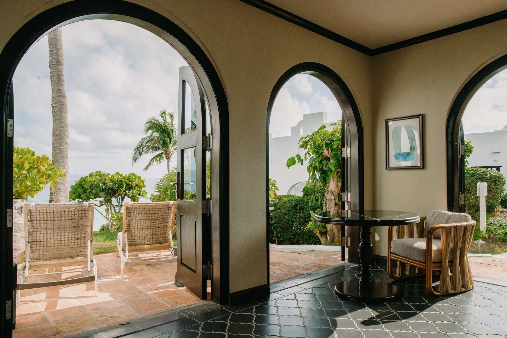 Arched doors open from a sitting area to a patio and sea view at Cap Juluca, Anguilla.