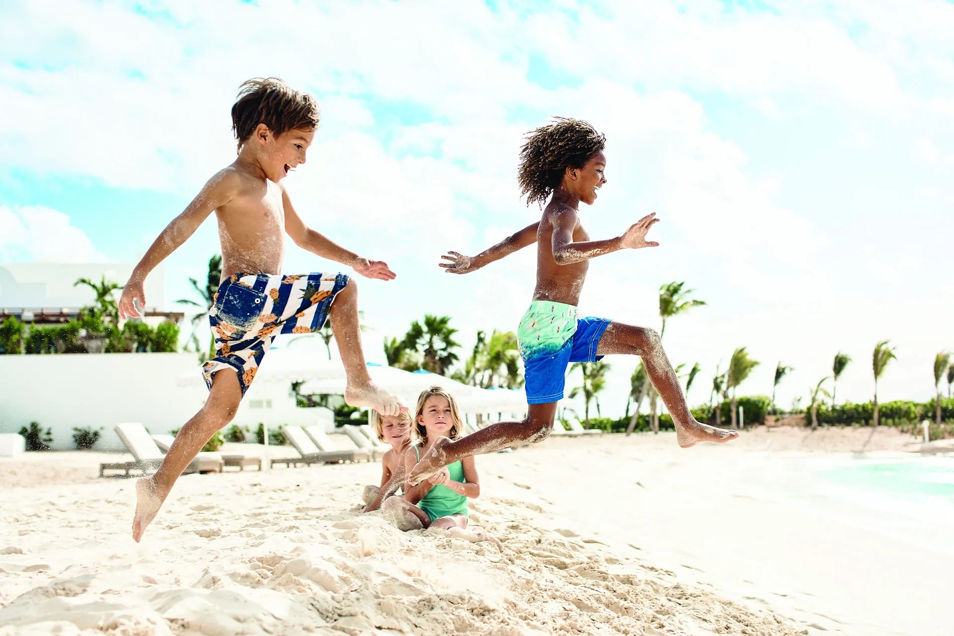 Children jumping in the sand on the beach at Cap Juluca, Anguilla.