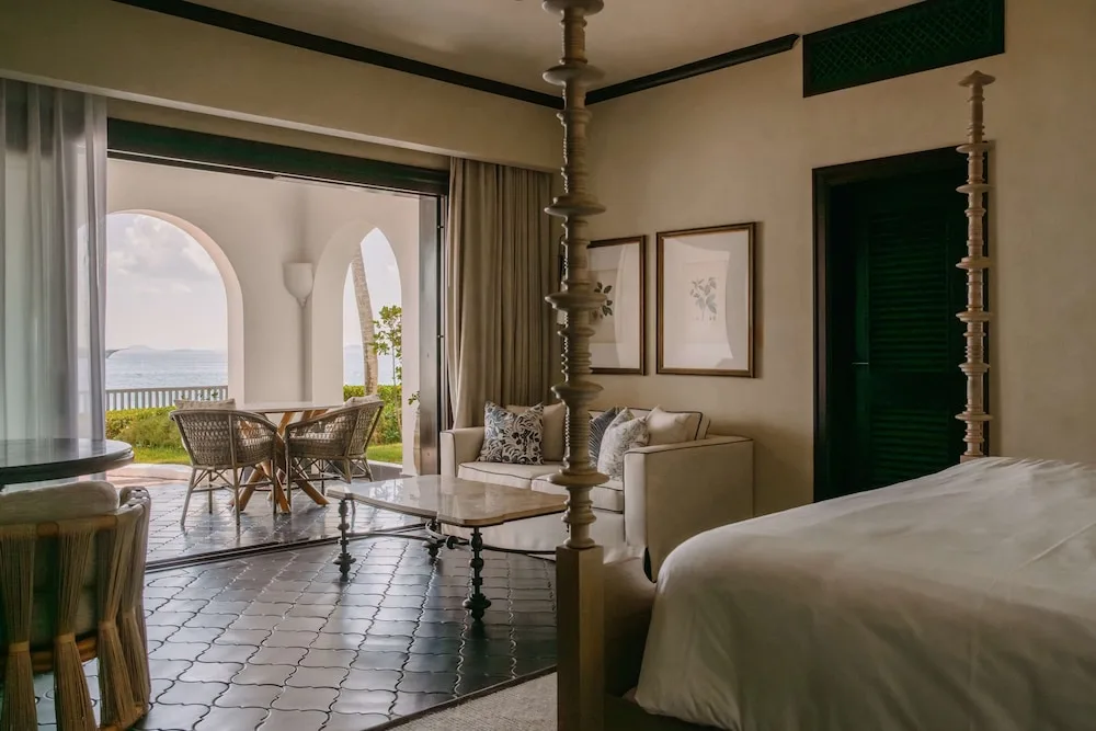 Guest room with bed, sofa, and arched terrace by the water at Cap Juluca, Anguilla.