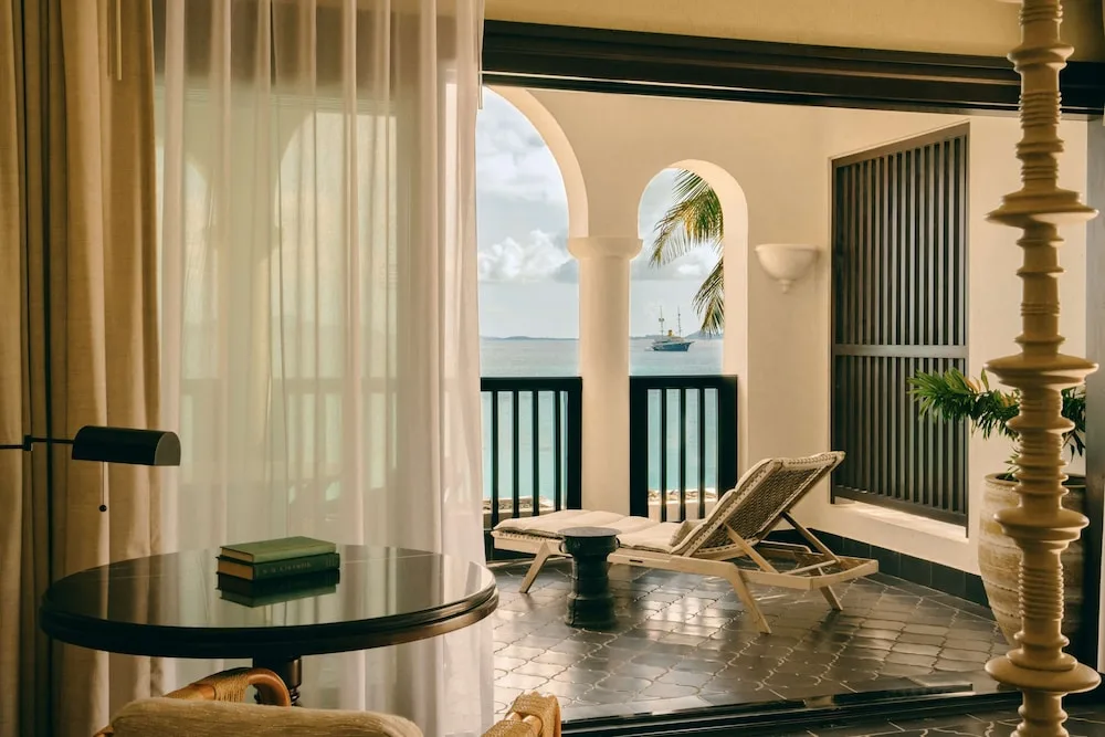 Covered terrace with lounge chair and sea view from a room at Cap Juluca, Anguilla.