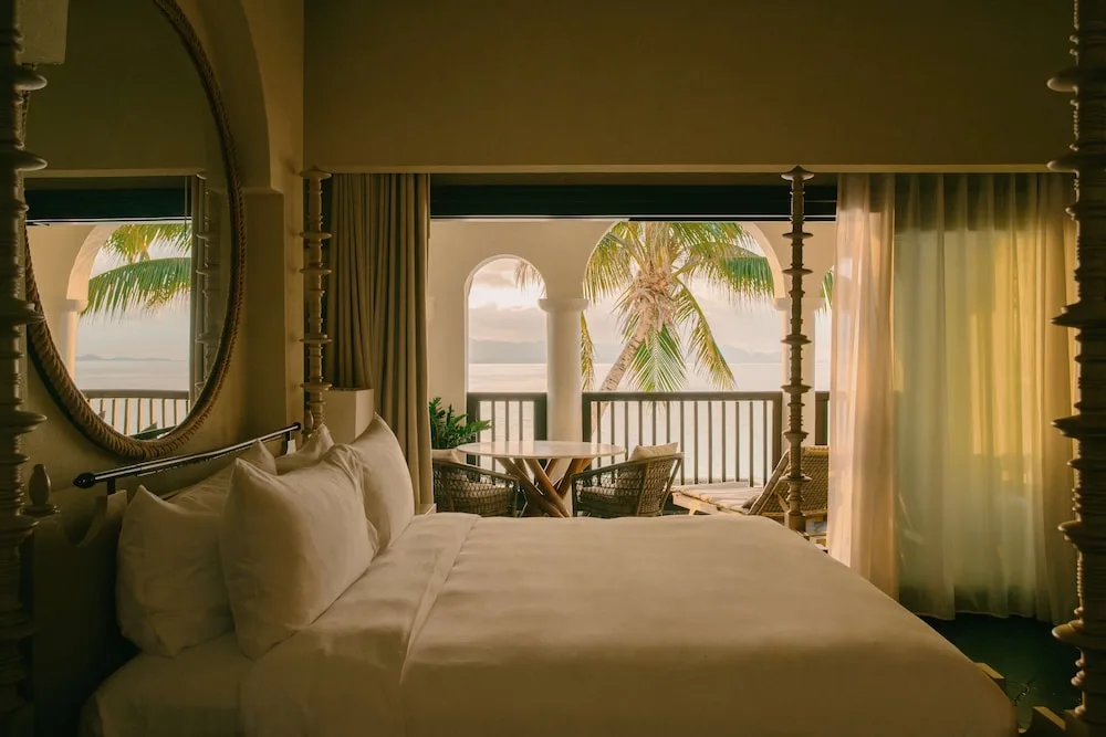 Four-poster bed opening to a palm-framed balcony at Cap Juluca, Anguilla.