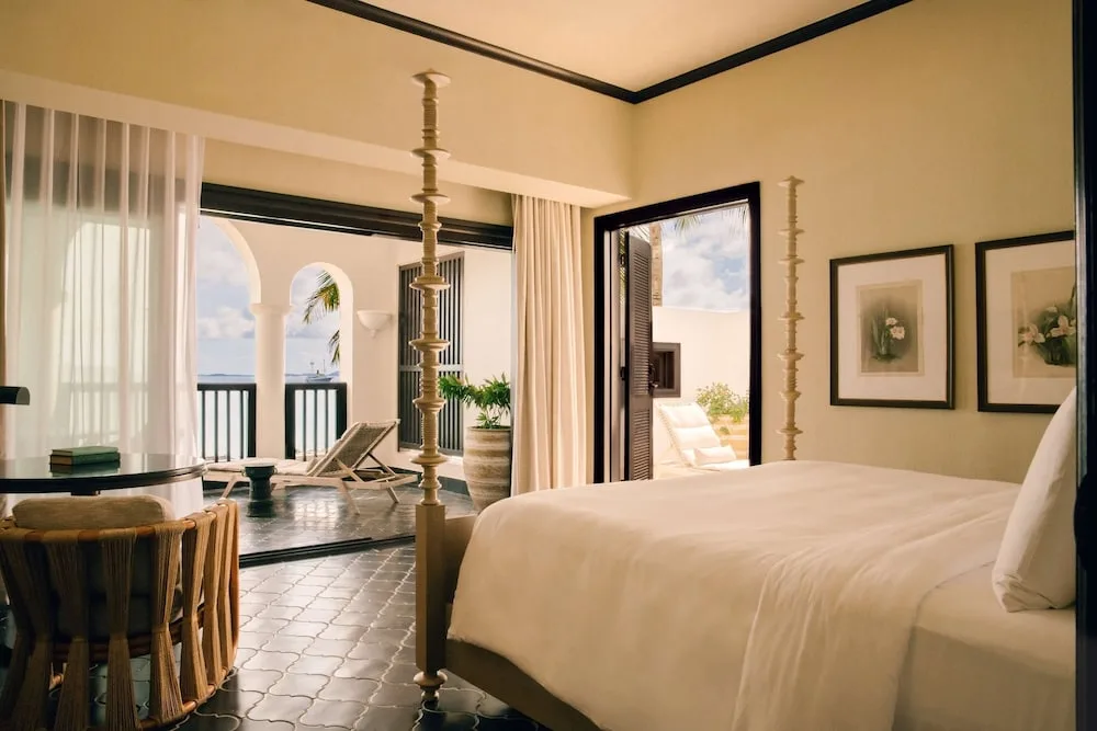 Guest room with four-poster bed and open terrace doors at Cap Juluca, Anguilla.