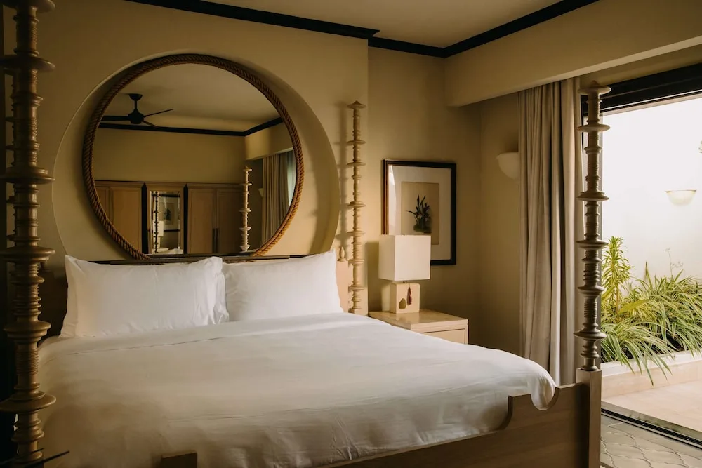 Four-poster bed with round mirror and garden-side doors at Cap Juluca, Anguilla.