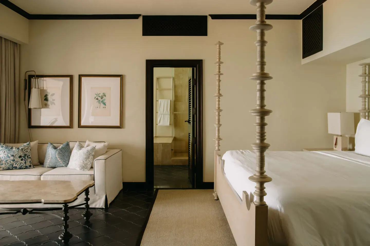Guest room with four-poster bed, sofa, and bathroom doorway at Cap Juluca, Anguilla.