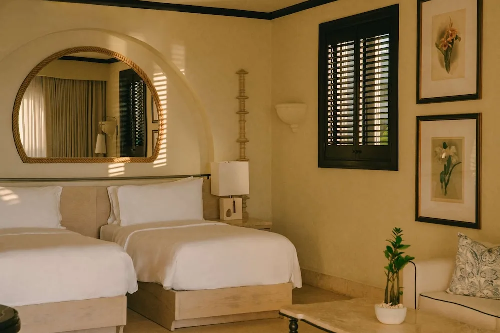 Twin-bed guest room with mirror and botanical art at Cap Juluca, Anguilla.