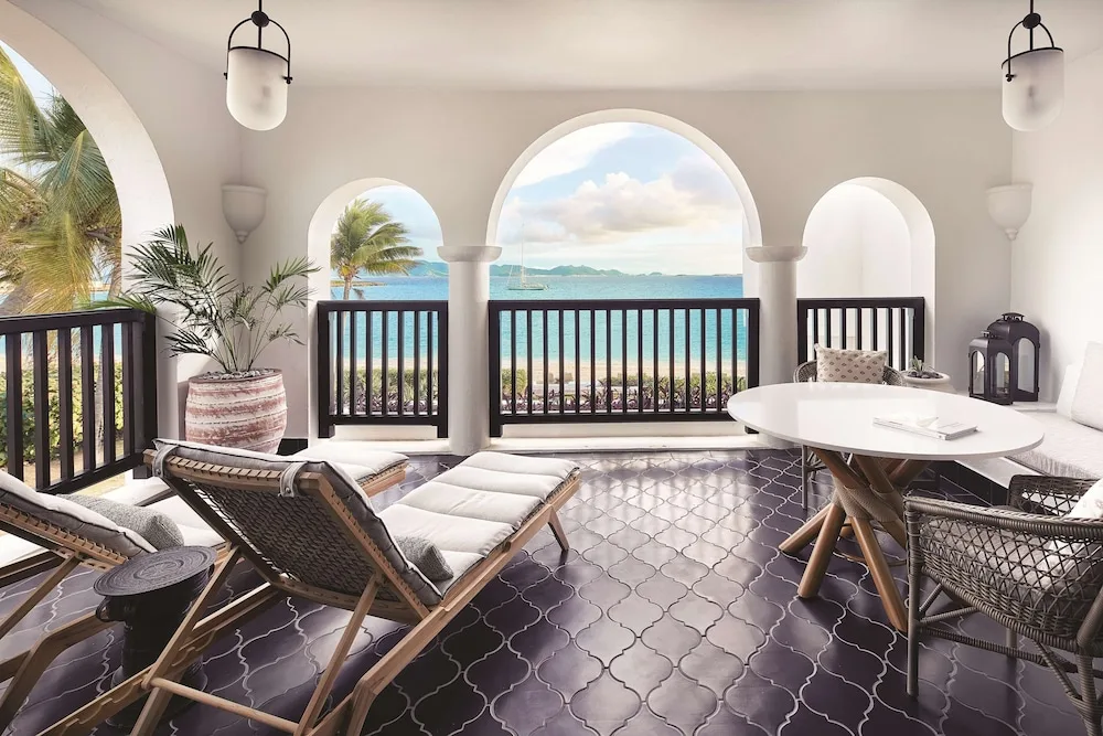 Arched oceanfront terrace with lounge chairs and dining table at Cap Juluca, Anguilla.