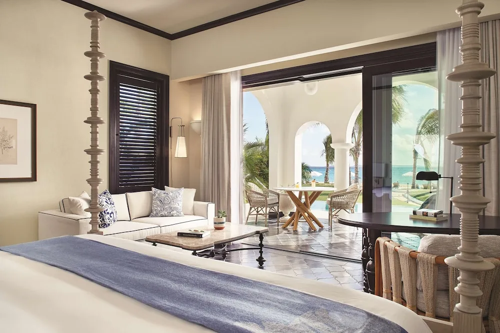 Guest room with four-poster bed and ocean-facing terrace at Cap Juluca, Anguilla.