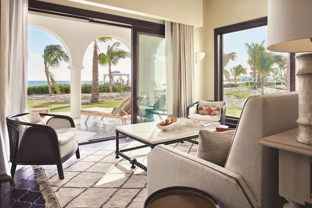 Guest room sitting area with terrace, palms and ocean beyond at Cap Juluca, Anguilla.