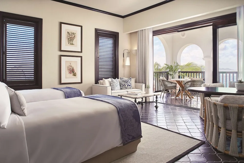 Guest room with twin beds, sofa and arched balcony view at Cap Juluca, Anguilla.