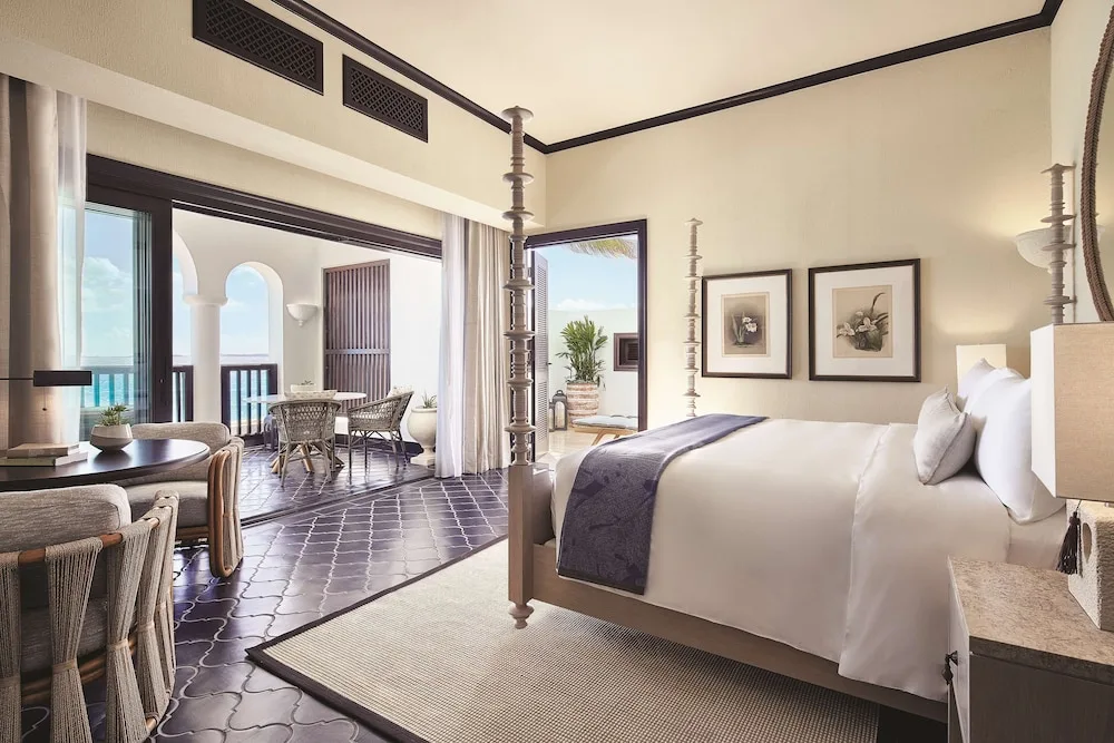 Guest room with four-poster bed, sitting area, and terrace at Cap Juluca, Anguilla.
