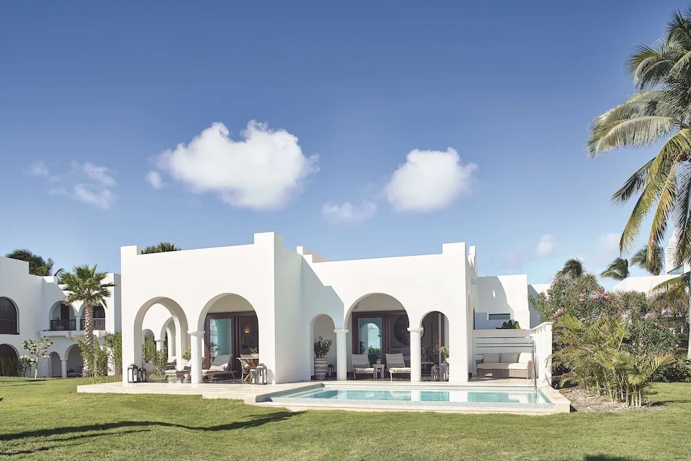 White villa exterior with lawn, arches, and private pool at Cap Juluca, Anguilla.