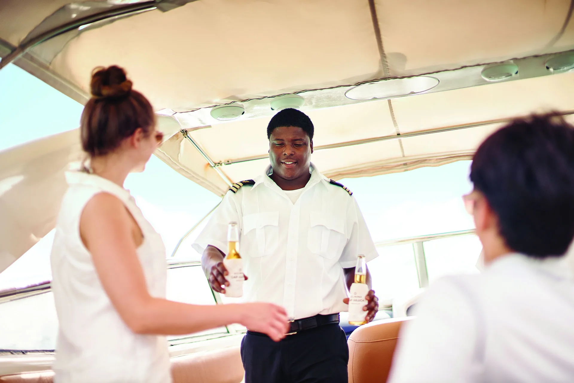 Boat crew member serving bottled drinks to guests aboard a yacht at Cap Juluca, Anguilla.