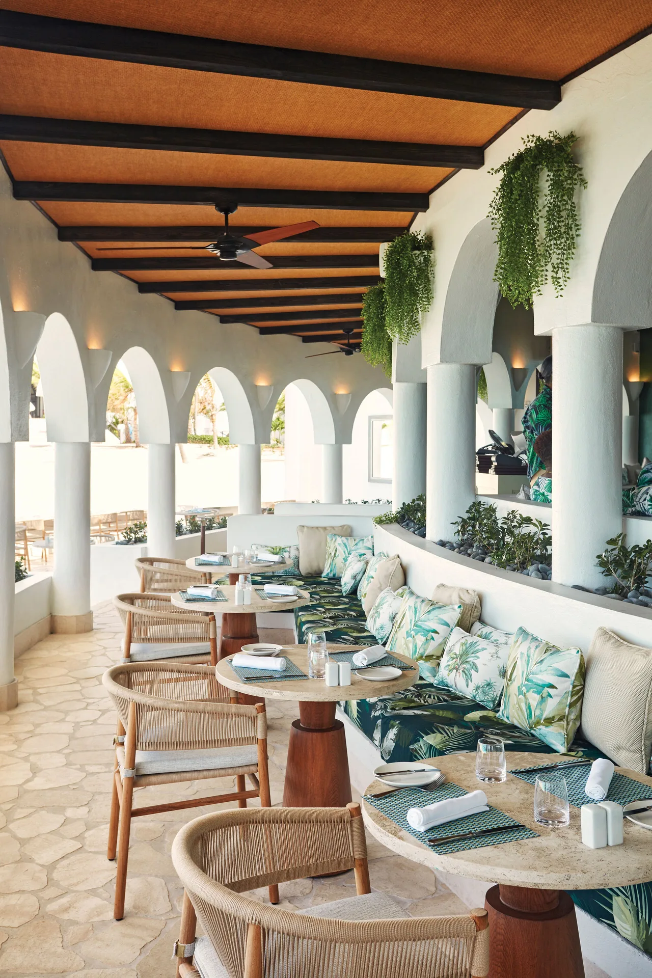 Covered terrace dining with arched openings and tropical cushions at Cap Juluca, Anguilla.