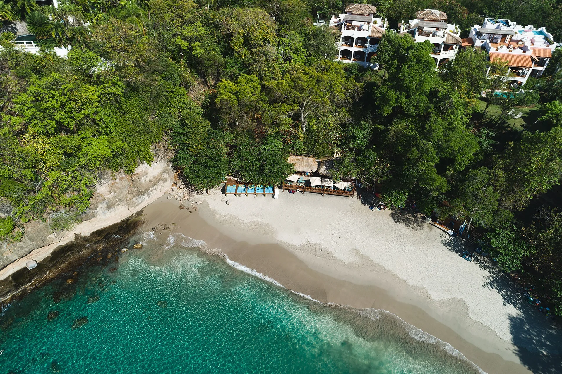 Aerial view of the beach and hillside resort buildings at Cap Maison Resort & Spa.