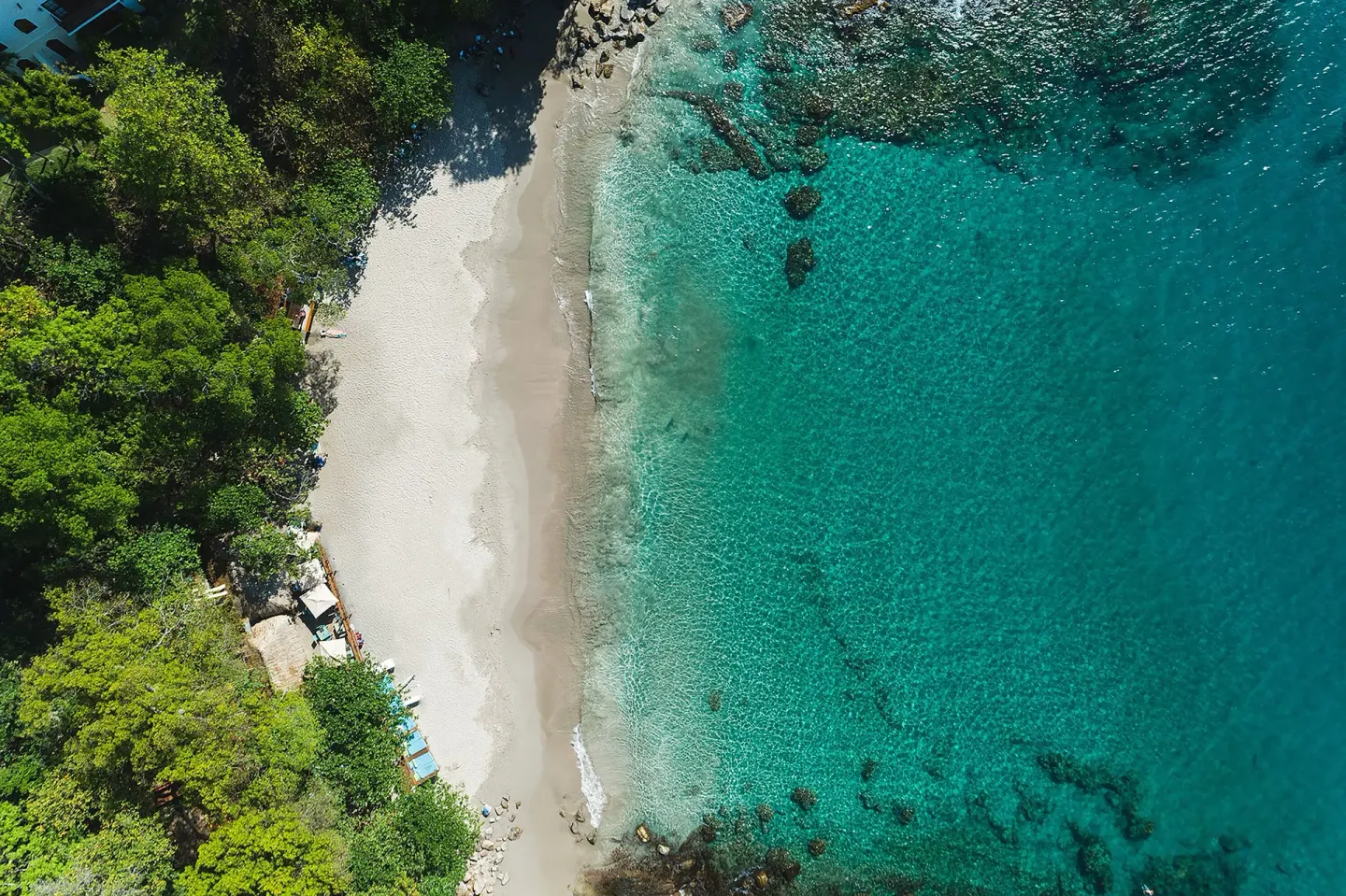 Aerial view of the sandy beach and clear turquoise water at Cap Maison Resort & Spa.