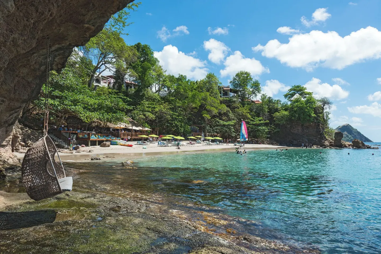 Beach cove with a hanging chair and sailboat at Cap Maison Resort & Spa.