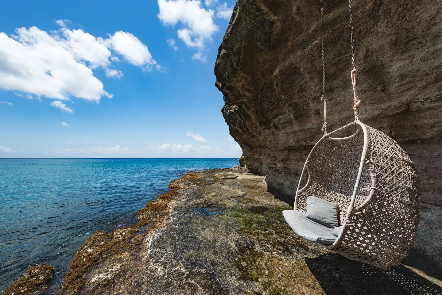 Cliffside hanging chair beside the sea at Cap Maison Resort & Spa.