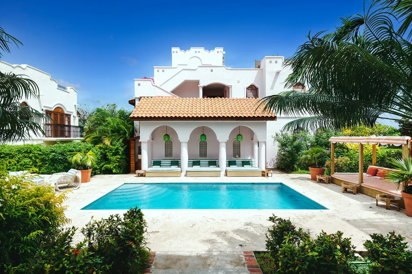 Courtyard pool framed by white buildings and palms at Cap Maison Resort & Spa.