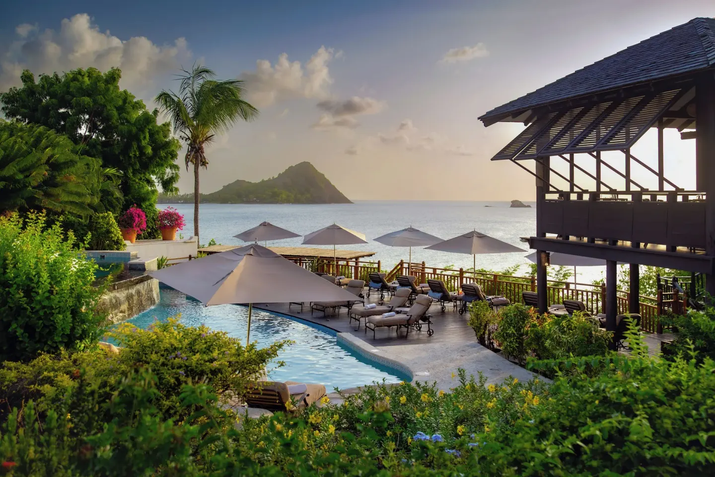 Pool deck with umbrellas, loungers, and ocean view at Cap Maison Resort & Spa.